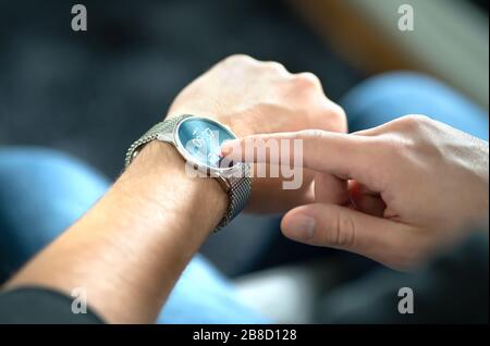 Man touching smart watch screen to open notification and read message. Wearable hybrid mobile device, gadget and activity tracker in wrist. Stock Photo