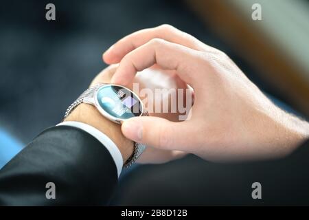 Smart watch with touch screen. Business man using wearable device with mobile technology. Smartwatch with finance report or banking app. Stock Photo