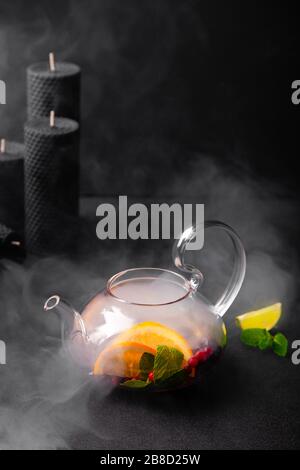 Pouring fruit tea in teapot with steam on black background Stock Photo