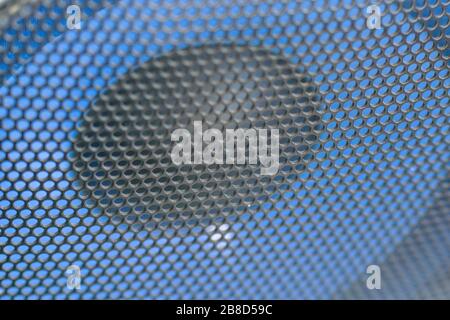 Fragment of the blue speaker with a black metal perforated grille. Audio speaker grill texture closeup view. Selective focus Stock Photo