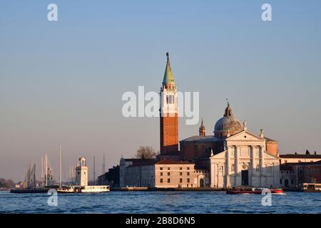 From de water view on the island of Saint Giorgio Maggiore during golden hour with dome and Campanile clearly visible against a blue sky Stock Photo