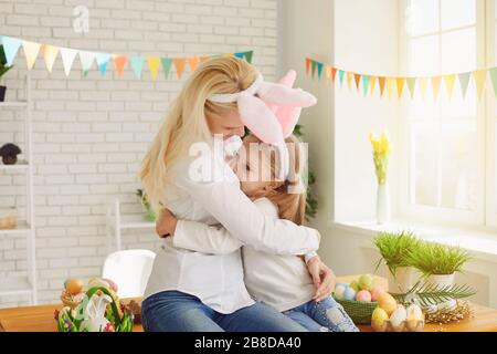 Happy easter. Daughter and mother with rabbit ears decorate Easter eggs sitting at a table Stock Photo