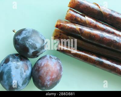 Sweet pureed fruit pastille. Fruit roll-ups homemade on a wooden background. Natural sweets from plum fruits. Stock Photo