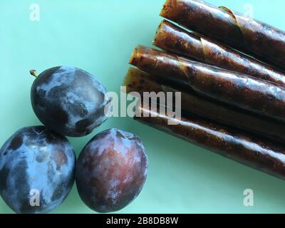 Sweet pureed fruit pastille. Fruit roll-ups homemade on a wooden background. Natural sweets from plum fruits. Stock Photo