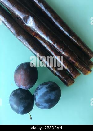 Sweet pureed fruit pastille. Fruit roll-ups homemade on a wooden background. Natural sweets from plum fruits. Stock Photo