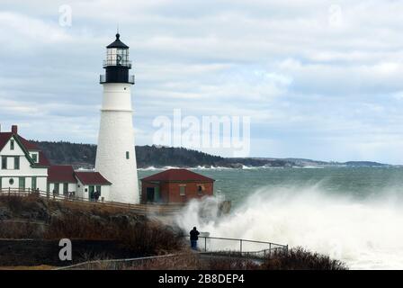 Giant waves crash by Portland Head lighthouse from rare high tides in late winter in Maine. Stock Photo