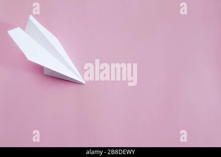 Flat lay white paper plane on pink background. Copy space.