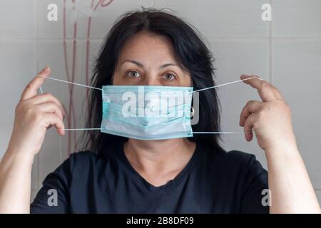 A woman puts on a mask to protect herself from viruses, including from a coronovirus. Copy space Stock Photo