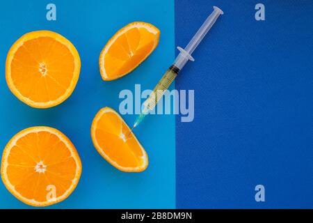 Vitamin C , syringe on fresh juicy orange fruit slides. Conceptual image of mineral,vitamin,medical supplement and health. Selective focus .Copy space Stock Photo