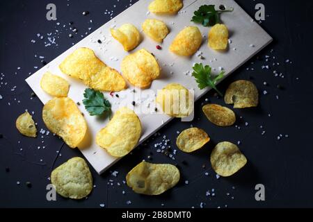potato chips, pepper mixture, sea salt on a dark table Stock Photo