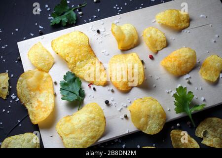 potato chips, pepper mixture, sea salt on a dark table Stock Photo