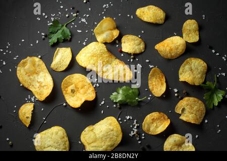 potato chips, pepper mixture, sea salt on a dark table Stock Photo