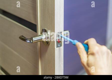 man repairing the doorknob with screwdriver. worker's hand installing new door locker Stock Photo