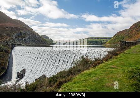 The Caban Coch Dam in the Elan Valley. Photographed after torrential rain with water cascading over the dam. Stock Photo