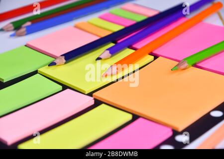 Colored pencils on a block of bright multicolored stickers Stock Photo