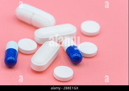 Various white and blue pills on pink background with copy space. Different medical drugs .  Stock Photo