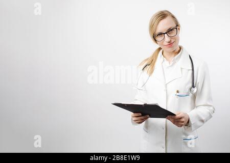 Woman in medical uniform standing in studio with clipboard Stock Photo