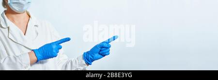 Female hands of a paramedic, nurse or doctor in blue gloves with copy space for product or text advertising. Medical face mask. Faceless banner. Prote Stock Photo