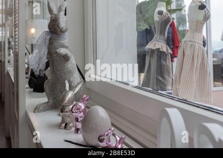 Silver easter bunnies sitting on sideboard. Bunnies sitting on sideboard in front of white bright window. Metal composition for Holiday concept. Stock Photo