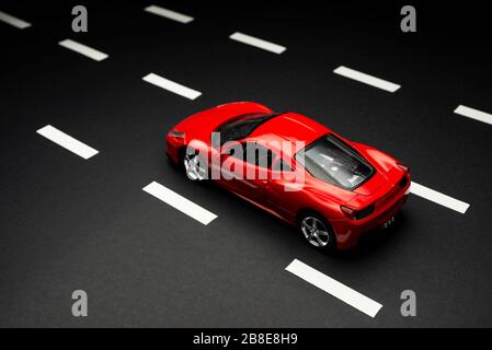 Izmir, Turkey - July 28, 2019: Top and rear view of Red toy sports car on an asphalt road with road lanes. Stock Photo