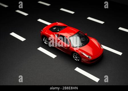 Izmir, Turkey - July 28, 2019: Top and front view of Red toy sports car on an asphalt road with road lanes. Stock Photo