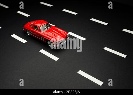 Izmir, Turkey - July 28, 2019: Mercedes 300 SL Red colored toy model car on an asphalt road with road lanes. Stock Photo