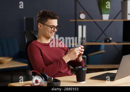 Young man using smartphone and smiling. Happy businessman using Stock Photo