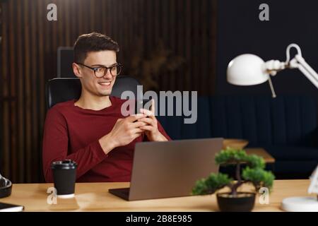 Young man using smartphone and smiling. Happy businessman using Stock Photo
