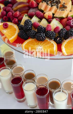 Close up of alcoholic cocktails on festive table with oranges, berries and different fresh fruits. Celebration or other event Stock Photo