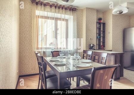 Prepared for dinner dining table at home. Nice small kitchen beige interior in daylight Stock Photo