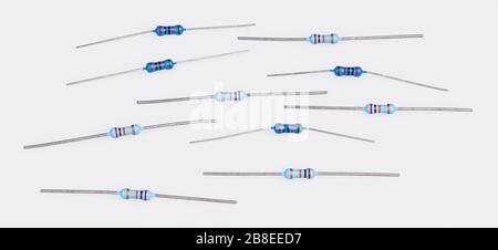 Set of blue miniature carbon resistors on white. Group of passive two terminal electrical components. Colorful bands of electronic standard color code. Stock Photo