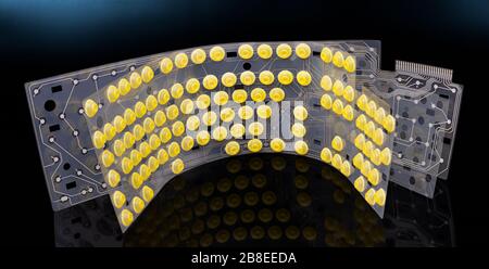 Round yellow buttons and electronic flex circuit board on plastic membranes. Inside of dismantled computer keyboard. Mirroring of rubber dome switches. Stock Photo