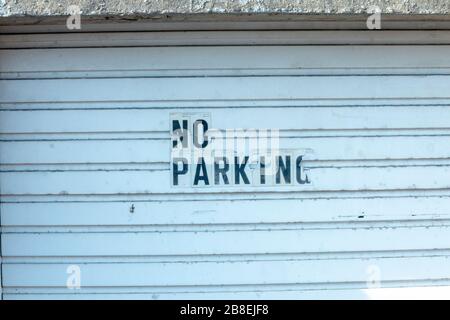 a close up view of a garage door that has a no parking sign that is slighlty damaged Stock Photo