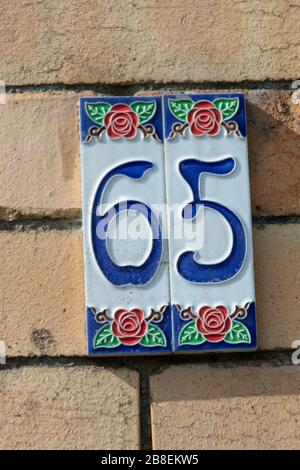 a close up view of the number sixty five embosed on a clay plate for outside your front door Stock Photo