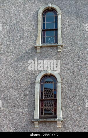 a close up view of two small stone windows on the side of a stone building Stock Photo