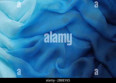 Blue draped silk fabric or scarf. Silk waves background. Stock Photo