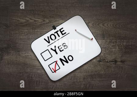 White board with the word Vote,Yes  and No Check boxes ,on a dark wooden background Stock Photo