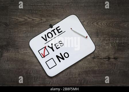 White board with the word Vote,Yes  and No Check boxes ,on a dark wooden background Stock Photo