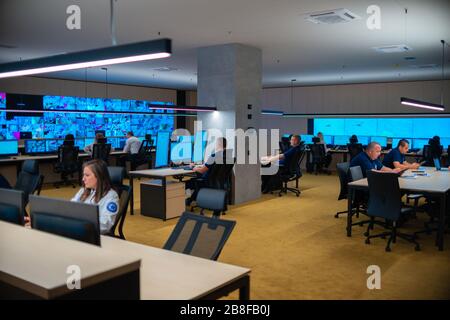 Group of Security data center operators (administrators) working in a group at a CCTV monitoring room while looking at multiple monitors ( computer sc Stock Photo