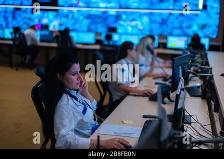 Group of Security data center operators (administrators) working in a group at a CCTV monitoring room while looking at multiple monitors ( computer sc Stock Photo