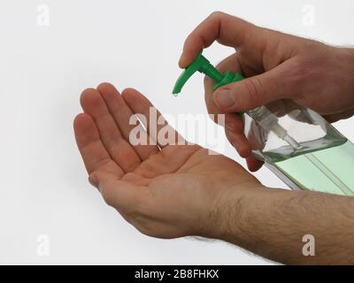 Antibacterial sanitizer gel in a plastic bottle is pumped into an awaiting hand; set against a dark background in a horizontal view. Stock Photo