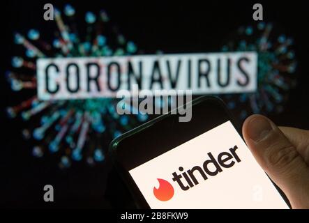 In this photo illustration the mobile dating app Tinder logo seen displayed on a smartphone with a computer model of the COVID-19 coronavirus on the background. Stock Photo