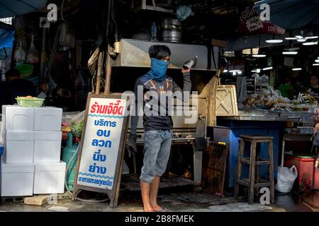 Heat protection facemask. Man wearing a heat protection facemask cooking on an open range in a Thailand street market. Stock Photo