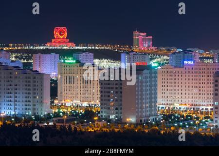 Ashgabat, Turkmenistan skyline at night. Wedding Palace, a civil registry building and Ashgabat Hotel visible. Multiple white marble buildings. Stock Photo