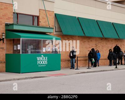 River Forest, Illinois, USA. 21st March, 2020. Shoppers line up outside a Whole Foods Market, keeping distance between them as a preventative measure against the spread of COVID-19. Governor Pritzker has implemented a 'Shelter In Place' order to go into effect at 5pm local time today.