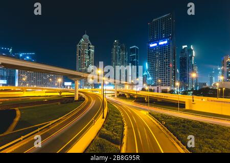 Long exposure of cars passing on highway at night in front of skyscrapers Dubai - UAE Stock Photo