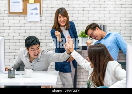 Group Of Asian Business people celebrating and giving high five together with happiness action and in the modern Office, Project succeed and teamwork Stock Photo
