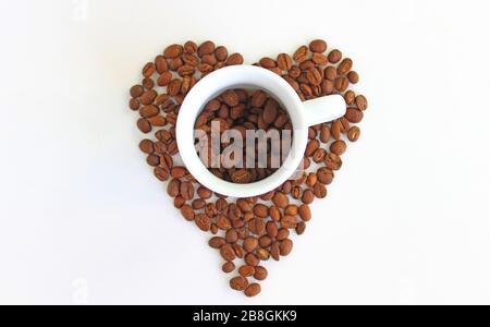 Roasted coffee beans in the shape of the heart and ceramic cup Stock Photo