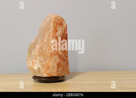 Turned off a Himalayan pink salt lamp carved in the shape of a rock on a light table. Stock Photo