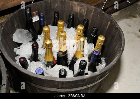 A wooden tub of ice with a collection of champagne and wine bottles at a wedding Stock Photo